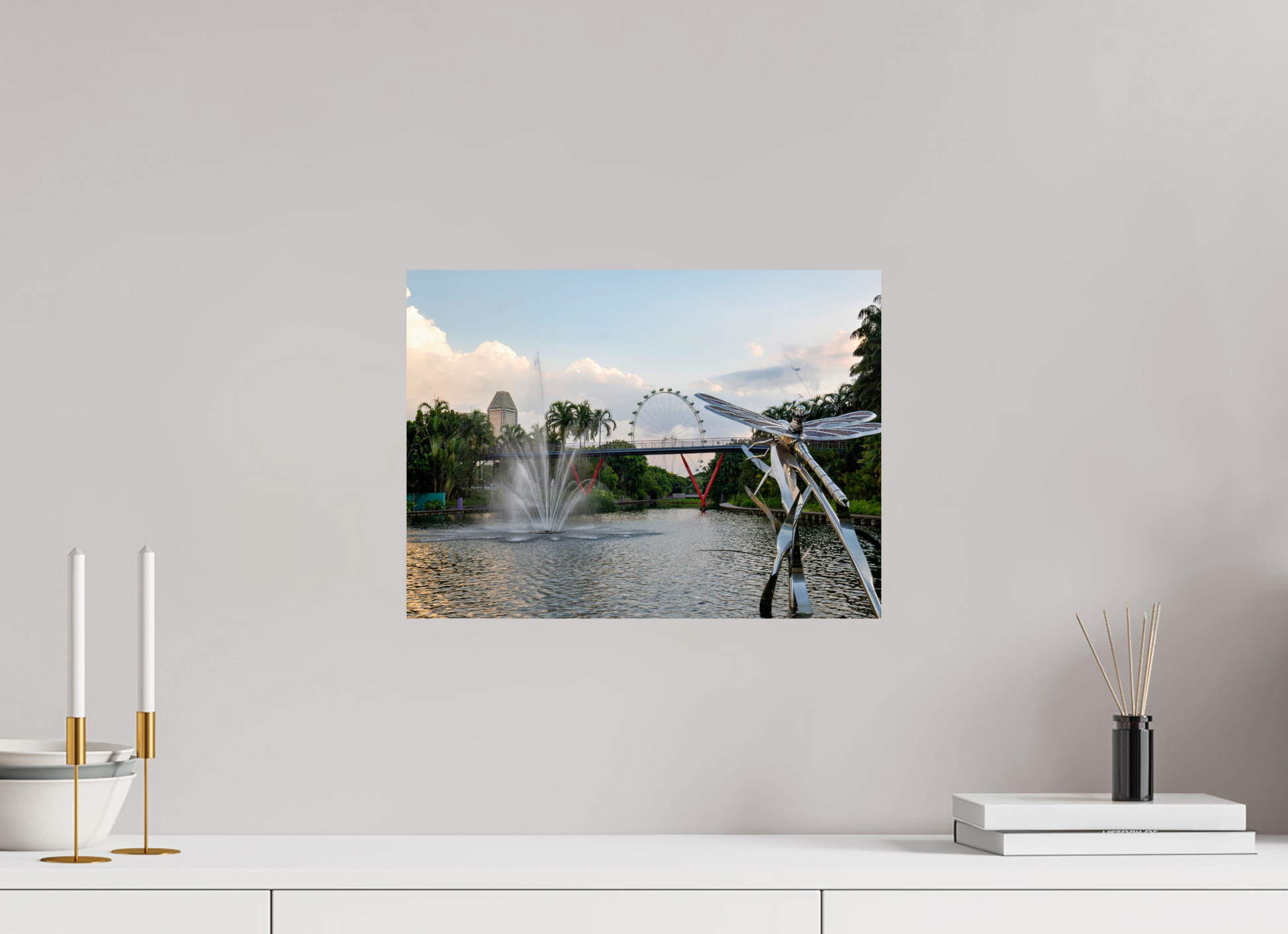 Framed photograph of a park scene with a lake, fountain, and Ferris wheel on a wall above a white shelf.